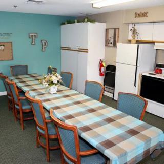 A cozy kitchen and dining area with a long table and multiple chairs, equipped with kitchen appliances.