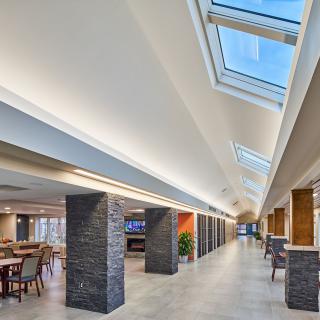 A modern interior featuring a spacious corridor with skylights and a dining area.