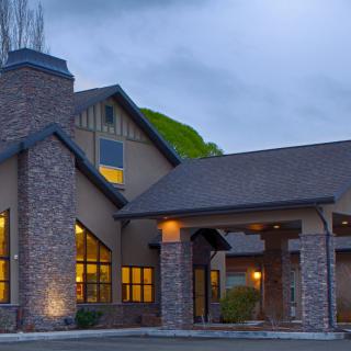A cozy residential house with illuminated windows and a chimney at dusk.