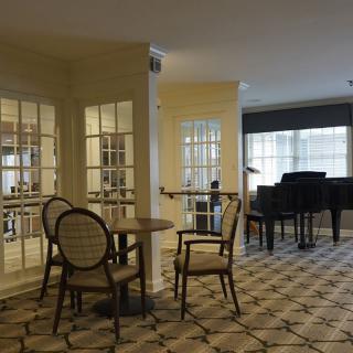 A cozy indoor setting with a piano, chairs, and a table.