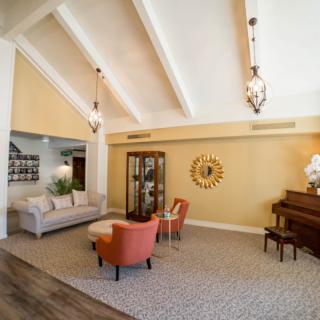 A cozy living room with vaulted ceilings, elegant lighting, and a piano.