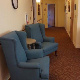 A cozy hallway with blue armchairs and warm lighting.