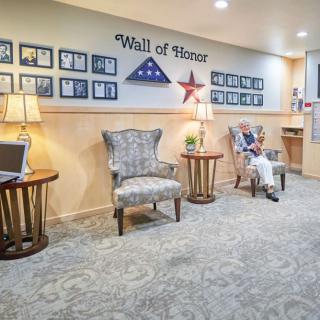 A lobby area featuring a 'Wall of Honor' with framed photos, patriotic decor, and comfortable seating.