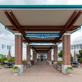 Entrance to the Rehabilitation & Health Center, featuring a welcoming walkway and outdoor seating.
