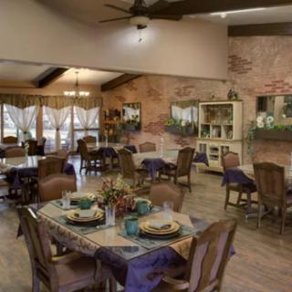 A cozy dining room with rustic decor, featuring multiple tables and wooden chairs arranged neatly.