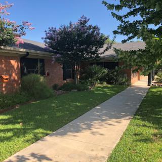 A charming house with a well-maintained front yard and walkway under a clear blue sky.
