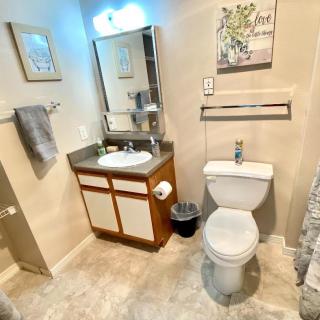 A neatly organized bathroom with a sink, mirror, toilet, and decorative elements.