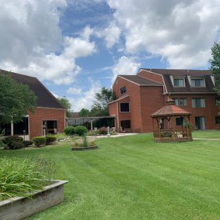 A peaceful outdoor area featuring brick buildings and well-kept gardens under a cloudy sky.