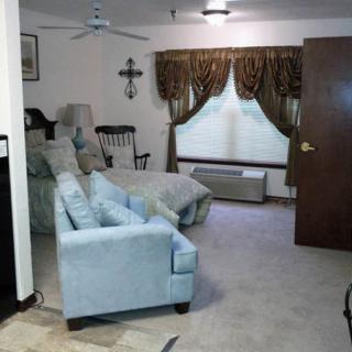 A cozy living room with a bed, armchair, and decorative curtains.