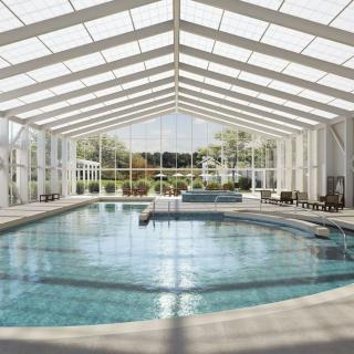 A spacious indoor swimming pool with a glass ceiling allowing natural light to fill the room.