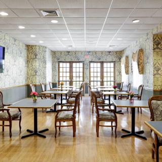 A neatly arranged restaurant dining area with wooden tables and chairs, featuring decorative walls and warm lighting.