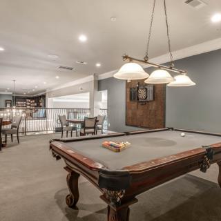 A stylish game room featuring a classic pool table under elegant lighting.