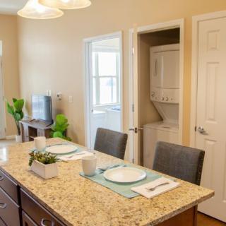 A modern kitchen with a granite countertop and neatly set dining area.