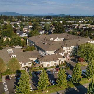 Aerial view of a residential building surrounded by trees and a parking lot in a suburban neighborhood.