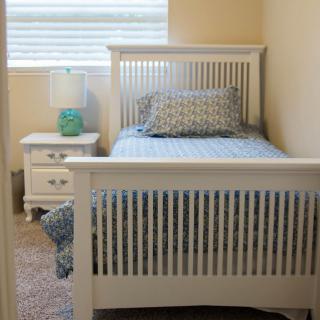 A cozy bedroom with a single bed, nightstand, and lamp.