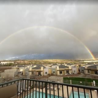 A panoramic view of a rainbow arching over a suburban neighborhood.