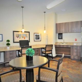 A modern dining area with a kitchenette, featuring stylish lighting and contemporary furniture.