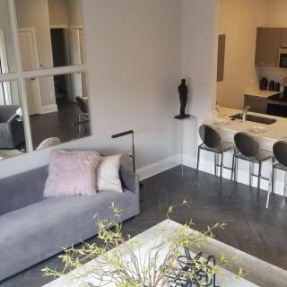 A modern, open-concept living room with a gray sofa and kitchen island.