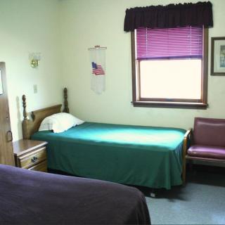 A simple hotel room interior with two twin beds and a window.