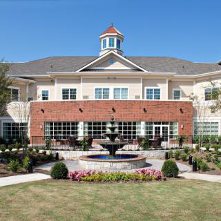 A symmetrical building with a central fountain and landscaped garden.