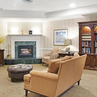 A cozy living room with a fireplace, sofa, armchair, and bookshelf.