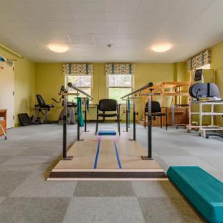 A rehabilitation room equipped with parallel bars and other physical therapy equipment.