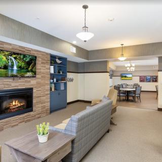 A modern living room with a cozy fireplace and a television mounted above, featuring stylish furniture and an open layout.