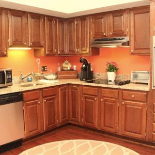 A modern kitchen with wooden cabinets and orange walls, featuring various appliances.