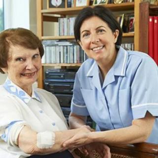 A caregiver attending to an elderly woman in a home setting.