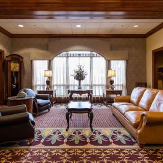 A well-furnished living room with elegant sofas, armchairs, and a coffee table set on a patterned rug.