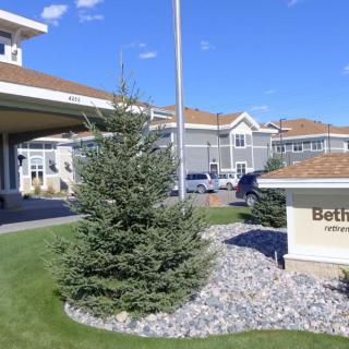 A modern building entrance with landscaped greenery and clear signage.