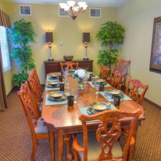 A well-decorated dining room with a large wooden table set for a meal and surrounded by matching chairs.