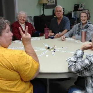 A group of people sitting around a table, engaging in conversation and enjoying each other's company.