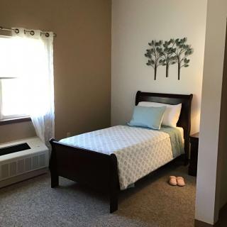 A minimalist bedroom with a single bed and soft natural lighting.