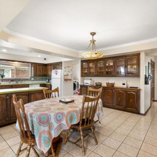 A cozy kitchen and dining area featuring wooden cabinets, a round table with a patterned tablecloth, and a chandelier overhead.