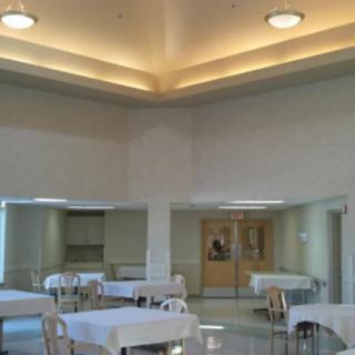 An empty dining area with tables and chairs under bright ceiling lights.