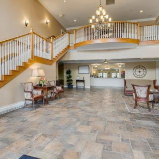 A spacious lobby with a grand staircase, chandelier, and comfortable seating area.