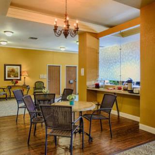 A cozy dining area with round tables, chairs, and a chandelier, set on a wooden floor.
