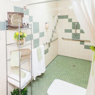 A well-designed bathroom featuring green tiles and accessibility features.
