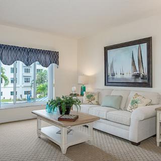 A cozy living room with a sofa, coffee table, and nautical-themed wall art.