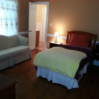 A cozy bedroom with a bed, sofa, and bedside lamp.
