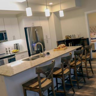 A modern kitchen featuring a central island with bar stools and pendant lighting.