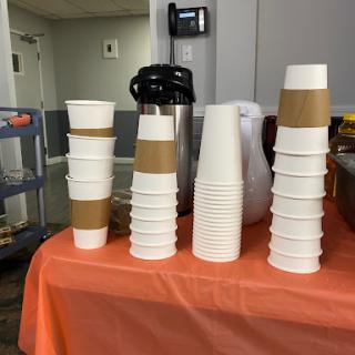 A neatly arranged display of stacked cups on an orange table, ready for a beverage service.