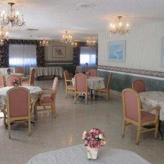 A spacious dining room with elegant chandeliers and neatly arranged tables.