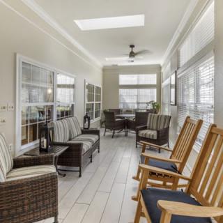 A cozy sunroom with ample natural light, featuring comfortable seating and rocking chairs.
