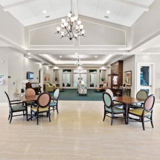 A spacious and elegantly furnished lobby with tables, chairs, and a chandelier.