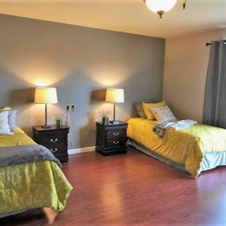 A cozy bedroom with twin beds, each accompanied by a nightstand and lamp, set against a hardwood floor.
