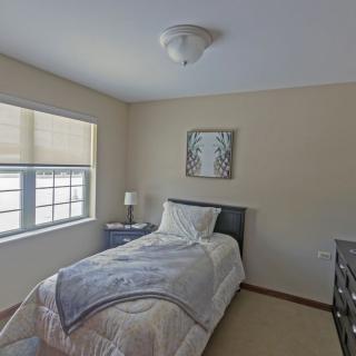 A minimalist bedroom with a single bed, nightstand, and decorative artwork.