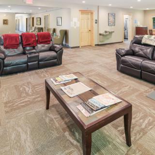 A cozy waiting room with comfortable couches and a coffee table stocked with magazines.