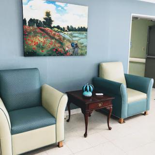 A cozy waiting area featuring comfortable chairs, a decorative table, and vibrant artwork.